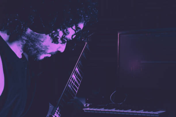 seitenansicht eines mannes im dunkeln, der e-gitarre spielt - gitarre grafiken stock-fotos und bilder