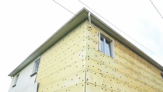 Exterior repair work on the building, insulation and cladding of the facade of the house. Insulation of a residential building