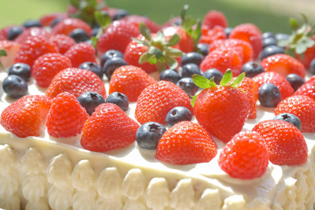 Homemade baking with fruits for Birthday, family event, Valentines day. Handmade white cream cake with fresh red berries on wood table. Ripe strawberry, raspberries and blueberries for decoration cake