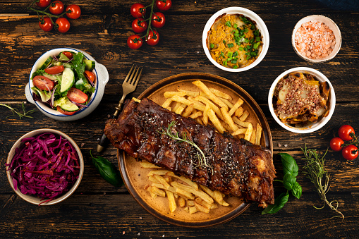 Grilled pork ribs with sauce , french fries, spices, wooden background