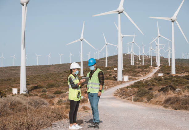 istock Engineers with protective face mask working on wind turbine in wind farm during pandemic 1373006669