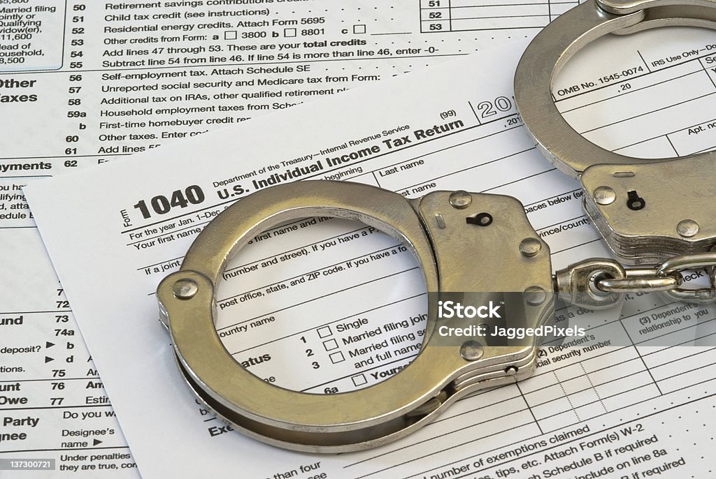 Tax Fraud or Slave to Taxes A 1040 income tax form with handcuffs. Tax Fraud or Slave to Taxes concepts. The year on the form is hidden to add to the image usefulness. Tax Form Stock Photo