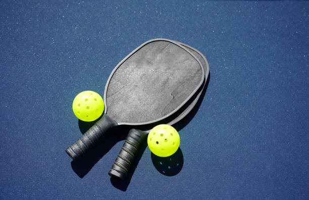 Pickleball Paddles on court Two pickleball paddles and two pickleballs on court pickleball stock pictures, royalty-free photos & images