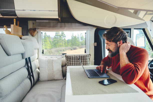 istock Young modern adult man work on laptop computer in remote working and digital job lifestyle inside a modern and connected camper van with nature woods view outside the window. Freedom lifestyle people 1373011663