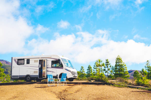 Beautiful tourism camper van campsite in the nature. Travel and rv renting vehicle vacation. Vanlife and wanderlust concept with modern motorhome parked in the nature with blue sky background hermoso camping de autocaravana de turismo en la naturaleza. vacaciones de viaje y alquiler de vehículos de alquiler de vehículos. concepto de vanlife y wanderlust con autocaravana moderna estacionada en la naturaleza con fondo de cielo azul