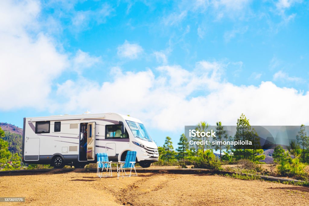 Beautiful tourism camper van campsite in the nature. Travel and rv renting vehicle vacation. Vanlife and wanderlust concept with modern motorhome parked in the nature with blue sky background Motor Home Stock Photo