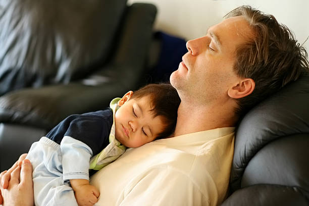 Baby sleeping on dad's chest Baby sleeping on dad's chest as he reclines on leather recliner man sleeping chair stock pictures, royalty-free photos & images