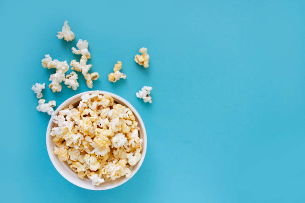istock Spilled popcorn on blue background. Movie night concept. Copy space for text 1373013385