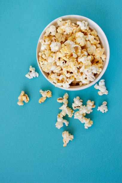 istock Spilled popcorn on blue background. Movie night concept. Copy space for text 1373013387