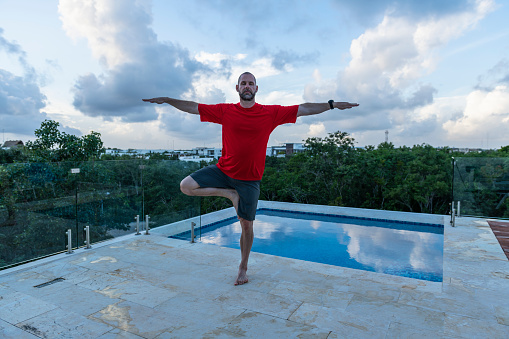 He balances in tree pose, while on a tropical holiday at a luxury hotel