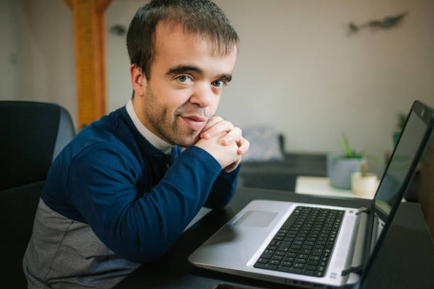 Young man with dwarfism working from home Young man with dwarfism working from home online dwarf stock pictures, royalty-free photos & images