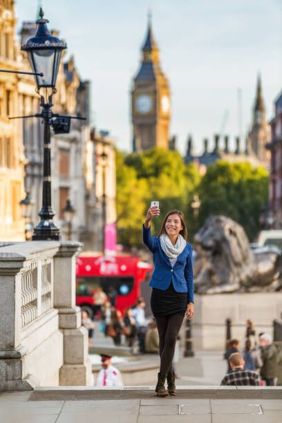 touriste de voyage à londres prenant une photo selfie avec téléphone portable près de big ben, royaume-uni. hommes d’affaires à trafalgar square, royaume-uni. vacances à destination de l’europe. - london england england big ben telephone photos et images de collection