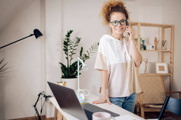 istock Beautiful redhead girl telephoning while freelancing from home 1373028644