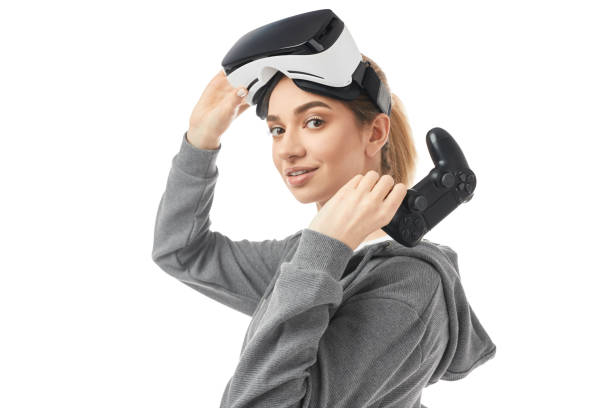 Happy young lady with VR headset and controller looking at camera in studio