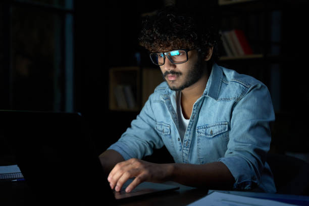 istock Focused young indian business man working online at night using laptop. 1373029583