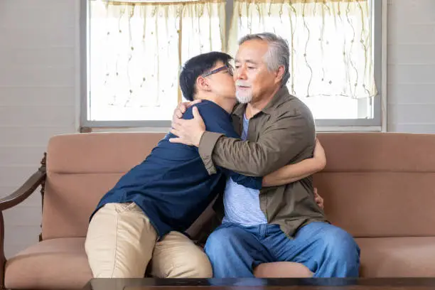 Senior Asian man embracing and listening to bad news from his son who just lost a job and come back home seeking for consolation and empathy from father