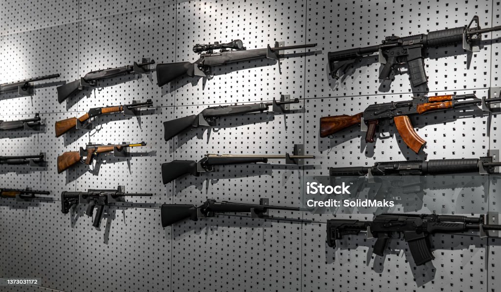 Collection of rifles and carbines. Various firearms hang on special mounts on the wall. Weapon background. Gun Stock Photo