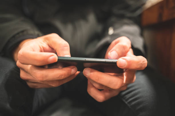 Hands of a casual man using a smartphone.