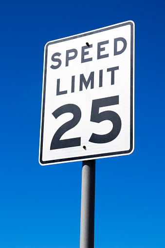 Close-up photo of a speed limit 25 sign against a blue background.
