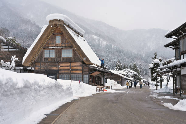 Tourists strolling in Shirakawago, Japan Shirakawago, Japan - February 24, 2022 : Tourists strolling on a snow-covered street in Shirakawago village in winter gifu prefecture stock pictures, royalty-free photos & images