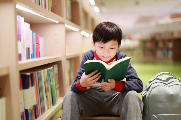 図書館のかわいい少年読書本 - bookstore student chinese ethnicity book ストックフォトと画像