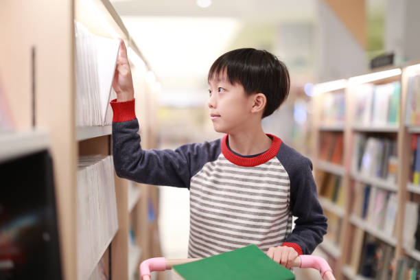 istock Cute boy reading book in library 1373041894