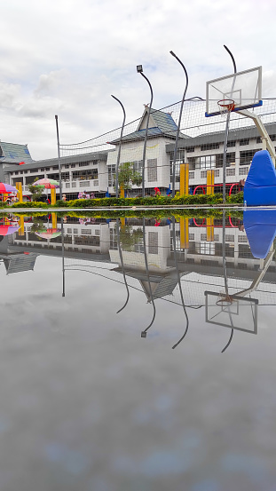 Cicalengka, West Java, Indonesia - February 10, 2022 :  Reflection of the public transportation terminal building from puddles in the Cicalengka square, Indonesia