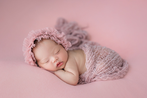 Happy adorable cute Asian newborn baby sleeping on pink background