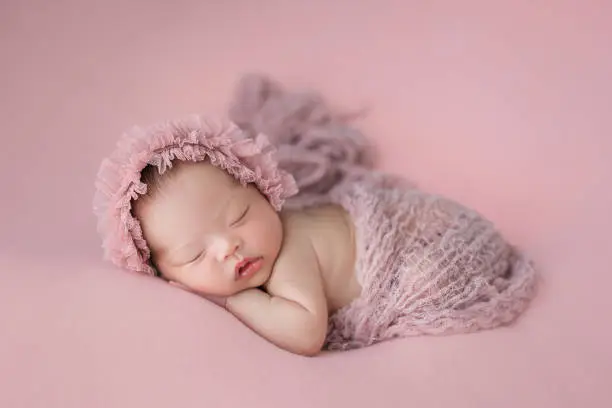 Happy adorable cute Asian newborn baby sleeping on pink background