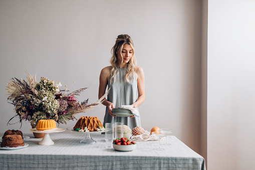 A smiling Caucasian woman setting the table for an elegant birthday party.