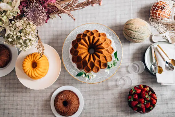 An elegant birthday party table is set! Delicious bundt and angel cake on a table with plates and spoons.