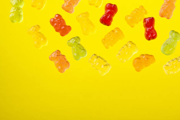 istock Multicolored flying gummy bears on yellow background, flat lay 1373056212