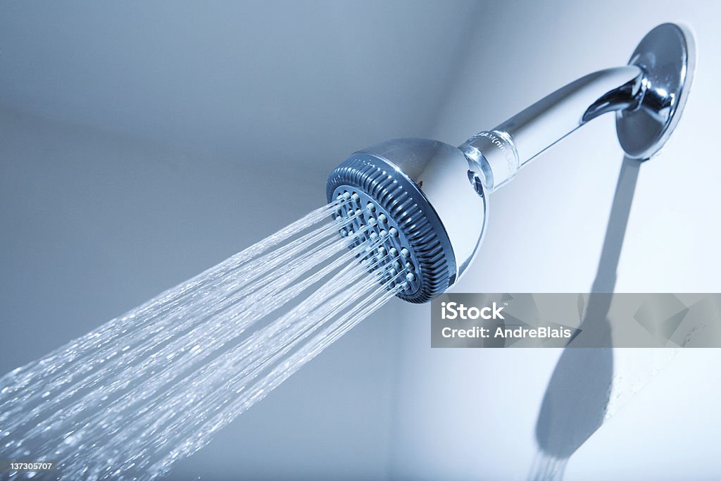 Shower Shower head with water stream on blue background Shower Head Stock Photo