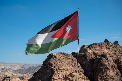Black, white, green and red flag of Jordan flying over the tourist destination of Petra