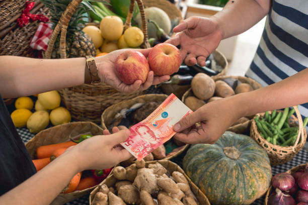 a man hands over a 50 peso bill to pay for two apples. buying fruits at a small market stall. - for sale industry farmers market market stall imagens e fotografias de stock