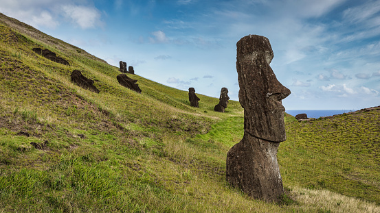 Rapa Nui Moai Statues from behind at Rano Raraku Volcanic Crater Landscape in summer on green hills. Easter Island, Rapa Nui, Rano Raraku, Chile