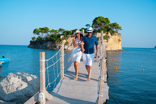 A happy smiling couple walking along a seashore, holding hands and laughing