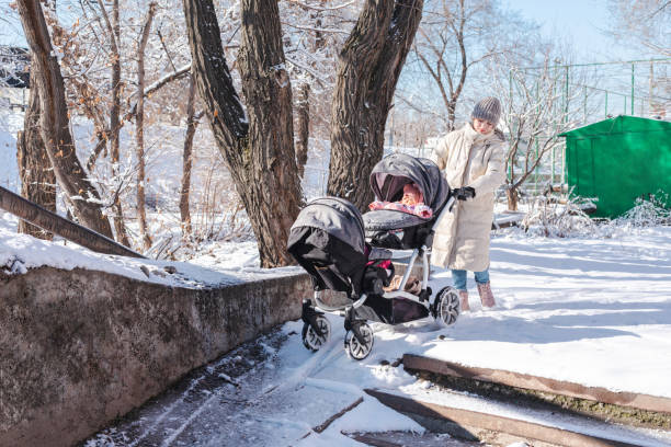 Mother struggling pushing baby stroller for twins going up the ramp in the snow Mother struggling pushing baby stroller for twins going up the ramp in the snow baby stroller winter stock pictures, royalty-free photos & images