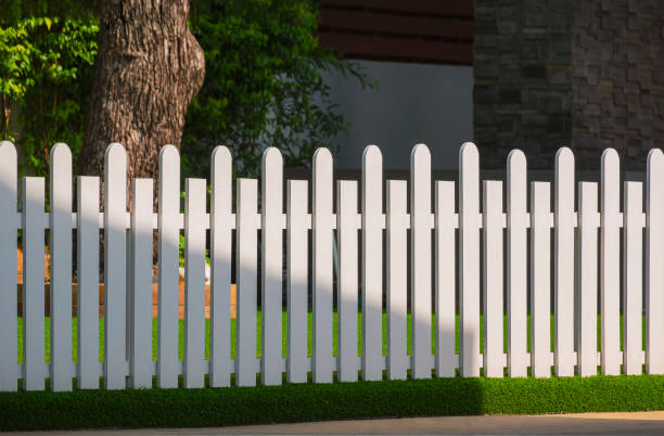 istock Front view of white wooden fence on artificial turf with sunlight and shadow on surface in front yard area 1373068252
