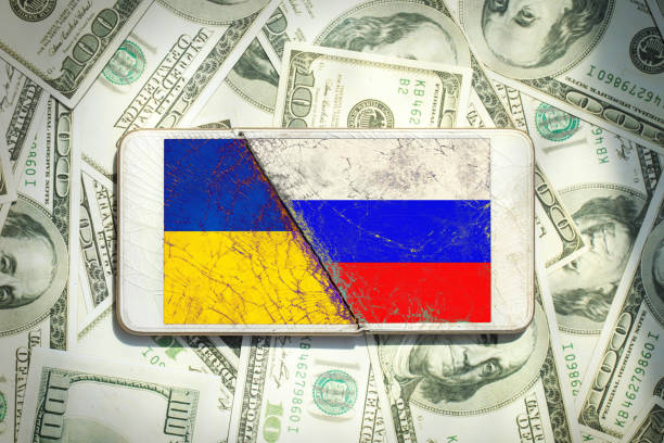 istock Ukraine vs Russia national flags icon pattern on the broken phone screen on a $100 dollar bill background.Ukraine US Russia politics economy relationship conflict.inflation 1373068315
