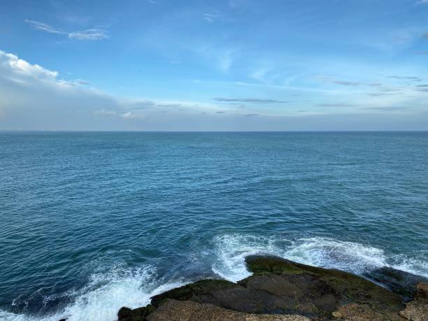 istock Waves crash on rocks with blue ocean and sky background 1373071373