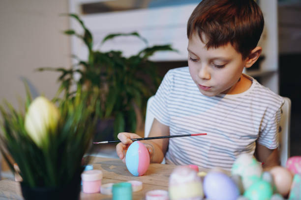 istock Cute little boy colouring eggs for easter 1373072058