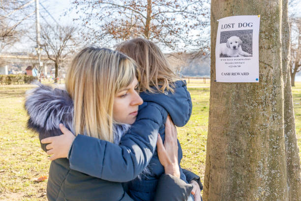 femme avec de la tristesse sur son visage embrassant sa fille bouleversée après avoir vu une affiche de chien perdu sur un arbre - lost pet photos et images de collection
