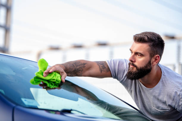 istock Young man cleaning his car with microfiber cloth 1373075080