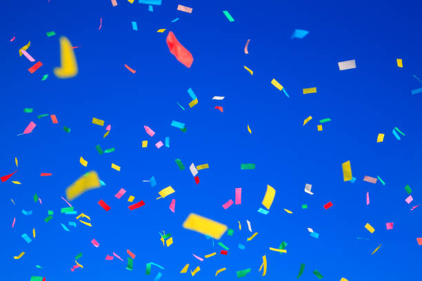 istock multicolored confetti on clear blue sky background. Concept of h 1373079820