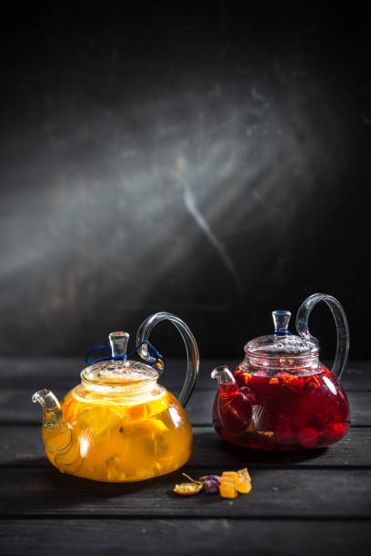 fresh tea with citrus and with strawberry in transparent teapot on a black wooden background stock photo