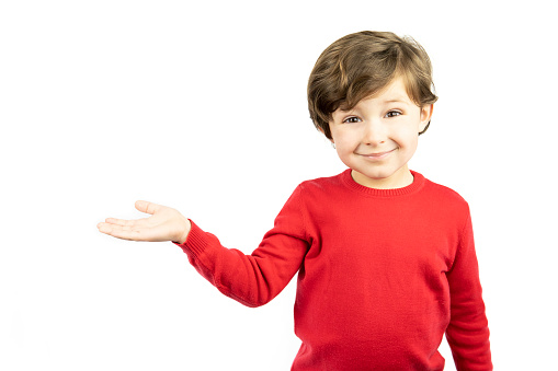 Child in red sweater pointing with hand on white background. Copy space.