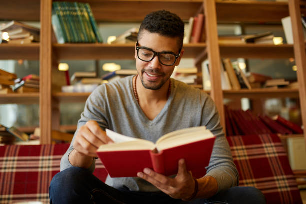 istock Smiling African American student enjoying book reading in library 1373085965