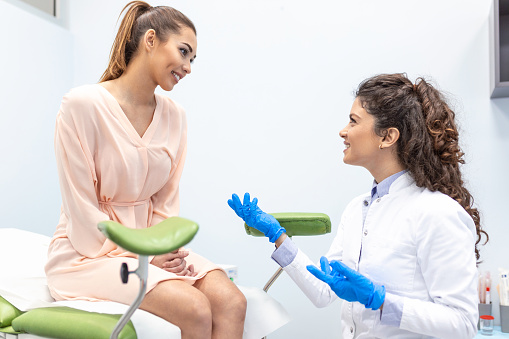 Ginecólogo hablando con una paciente joven durante una consulta médica en el consultorio ginecológico photo
