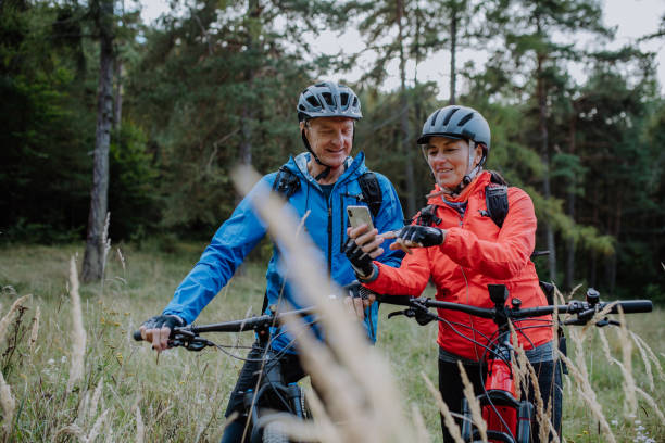 istock Senior couple bikers using smartphone outdoors in forest in autumn day. 1373089623